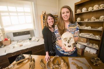 student standing with mentor while holding skull